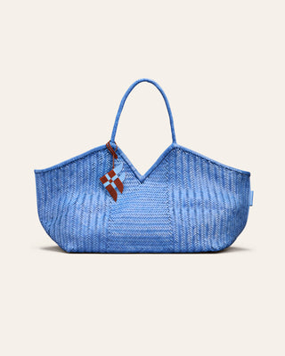 Blue woven handbag with a visible bag charm on a beige background