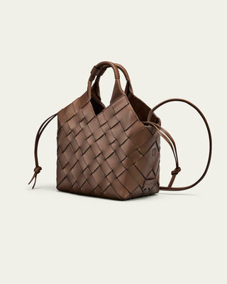 Brown woven handbag on a light beige background seen from the side