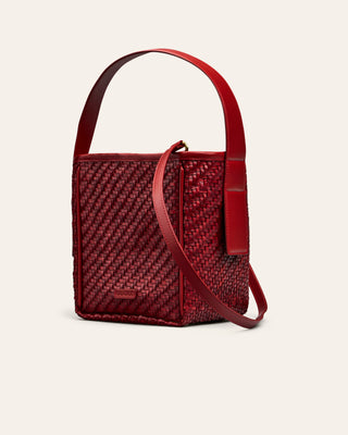 Cala Jade Iwa mini. Red woven leather handbag with a matching strap on a beige background