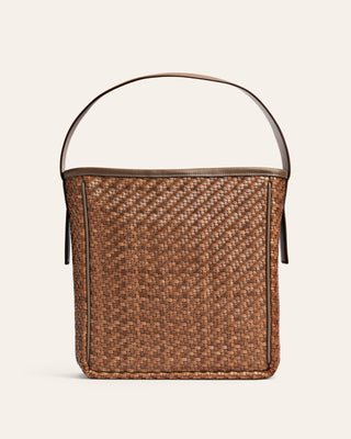 Woven beige bucket bag with shoulder strap on a beige background