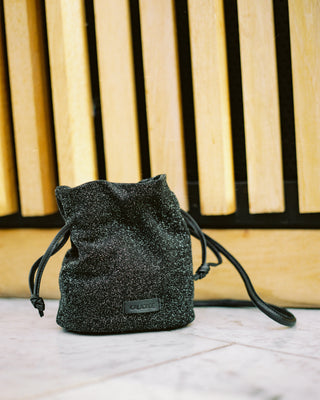 Black drawstring bag on a light wooden surface with a blurred background