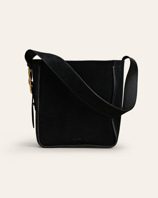 Black suede leather shoulder bag on a beige background