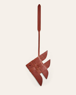 Cala Jade brown leather bag charm shaped like a fish on a beige background
