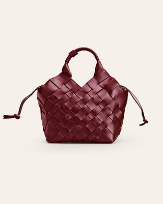 Burgundy woven handbag with drawstring on a beige background