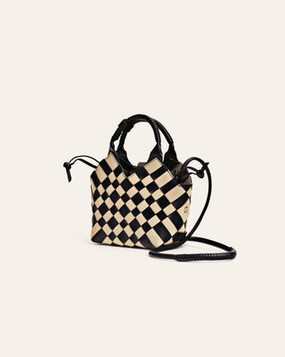 Black and beige leather checkered handbag with a strap on a light beige background