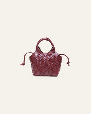 Burgundy woven leather handbag on a beige background