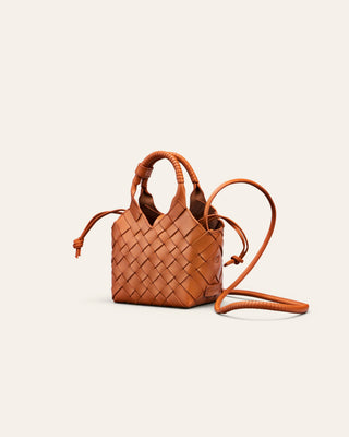 Cala Jade orange woven handbag with a strap on a light beige background seen from the side