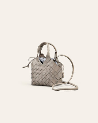 Woven handbag with a patterned cotton innterbag on a light beige background