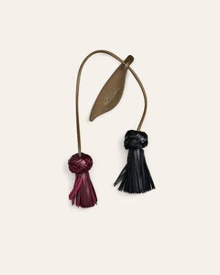 Cala Jade leather bag charm in green and burgundy shaped as a flower on a beige background