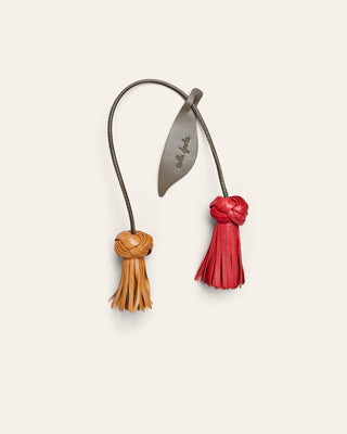Cala Jade leather bag charm in yellow and red shaped as a flower on a beige background