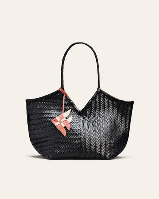 Cala Jade red and white leather bag charm shaped like a fish placed on a black tote bag on a beige background