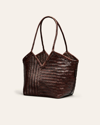 Woven handbag with leather handles on a light beige background
