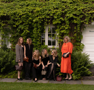 Group of women posing in front of a building with greenery