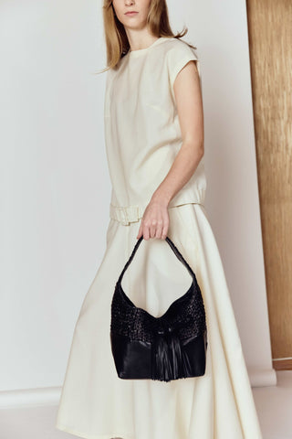 Woman holding a black handbag against a white background