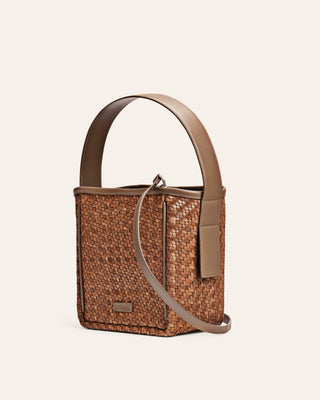 Brown woven handbag with a beige strap on a light beige background