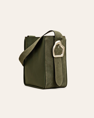 A forest green suede tote bag with a custom-made buckle, an adjustable shoulder strap on beige background