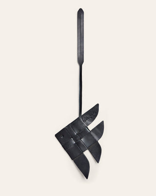 Cala Jade black leather bag charm shaped like a fish on a beige background