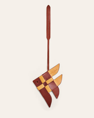 Cala Jade yellow and brown leather bag charm shaped like a fish on a beige background