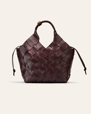 A burgundy woven leather bag on a beige background