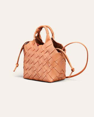 A light orange woven leather bag on a beige background