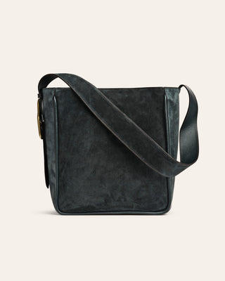 Dark green suede leather crossbody bag on a beige background