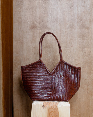 A brown leather bag on a wooden pidetstall