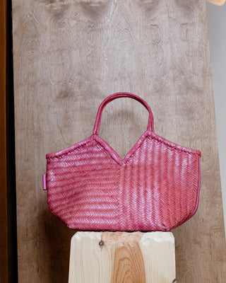A pink leather bag on a wooden pidestal