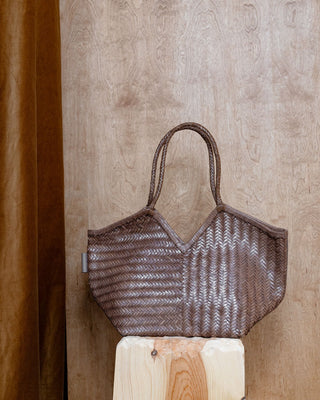 A beige leather bag standing on a wooden pidestal