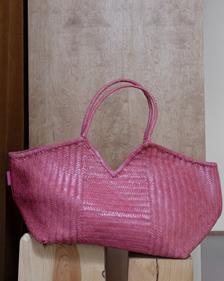 a pink leather bag on a wooden pidestal