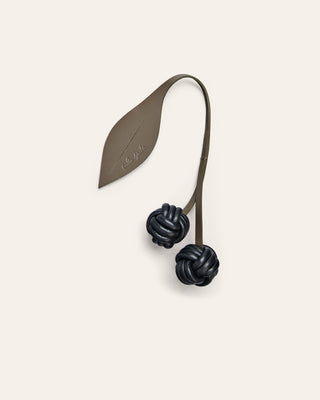 Cala Jade cherry leather bag charm in green and black on a beige background