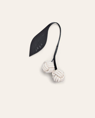 Cala Jade black and white cherry leather bag charm on a beige background