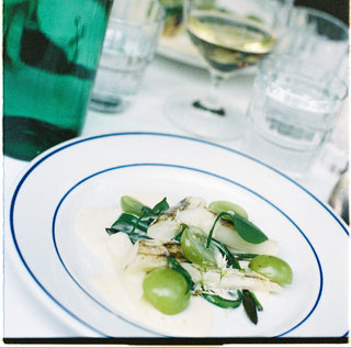 Dinner table setting with a plate of food, wine glasses, and a bottle.